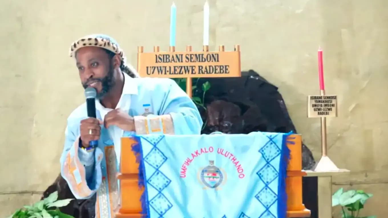 A faith leader in traditional dress addressing the gathering.